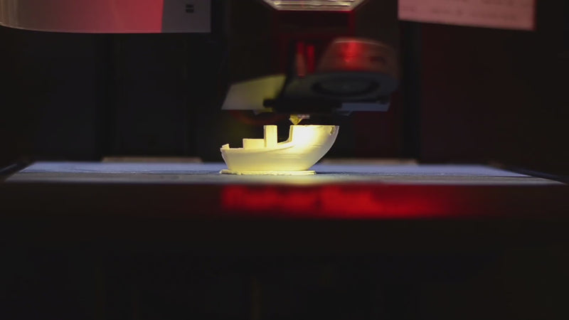 Close-up video of a 3D printer head moving smoothly on a gantry, building a partially completed 3D-printed boat. No sound.